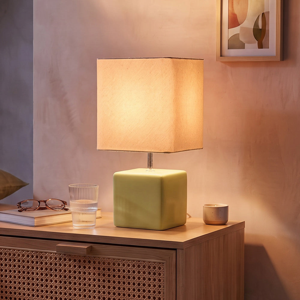 Abajur cubo verde pistache com cúpula de tecido aceso na mesa de cabeceira de quarto boho #verdepistache