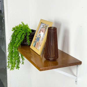 Prateleira de madeira com mão francesa branca decorada com planta, porta-retrato e vaso, Pratelar #branco